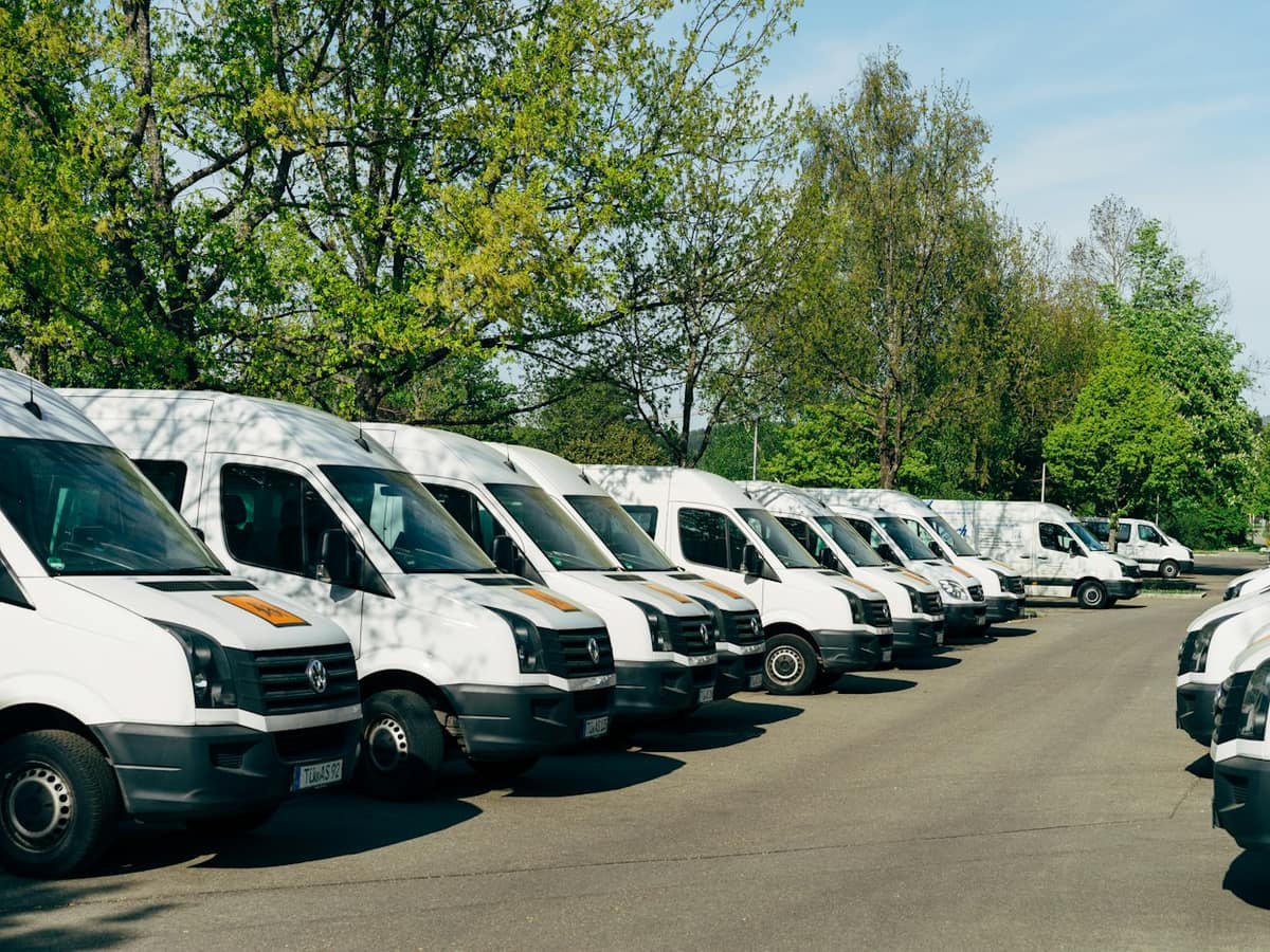 A row of white commercial vans parked in a fleet lot